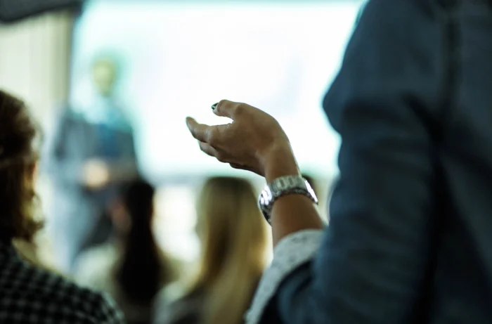 Blurred photo with a outreached hand in focus with a silver watch