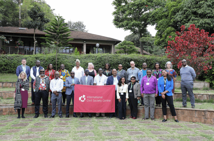Group photo of participants at an annual meeting, standing outside with the Centre banner in Nairobi