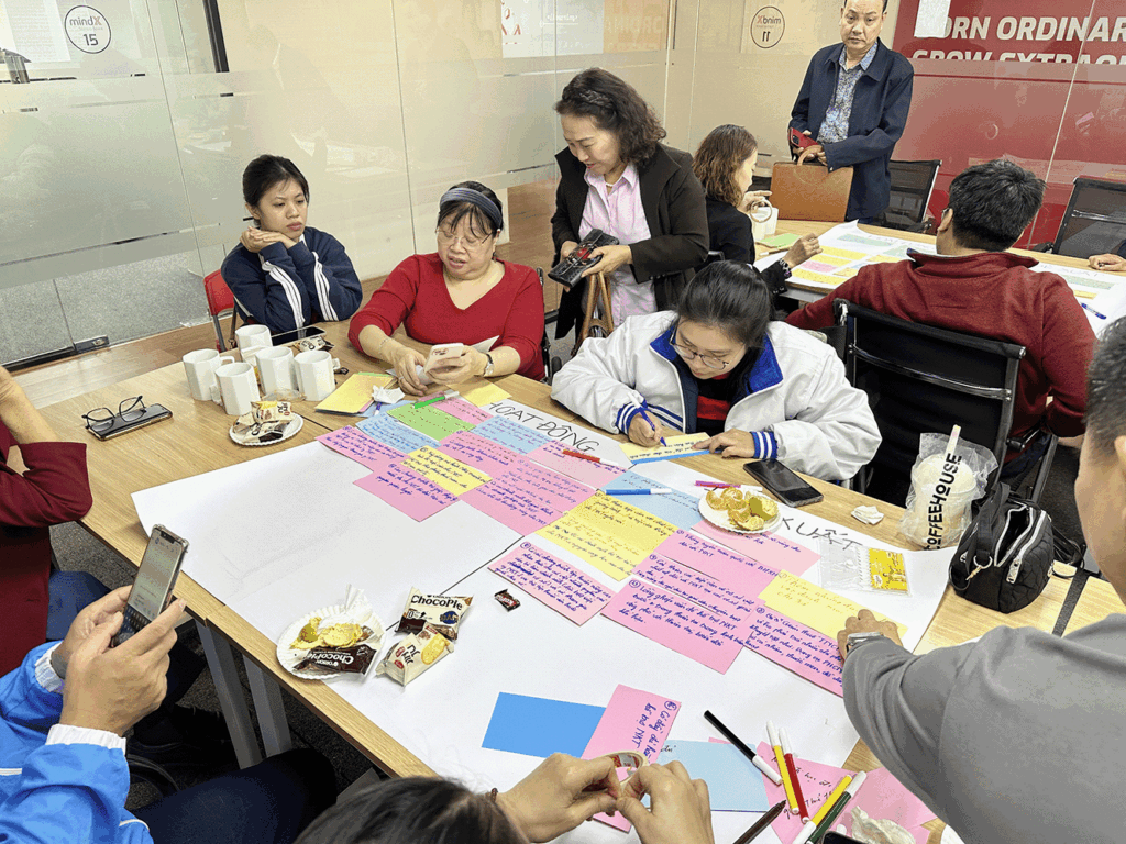 People sitting at a table with cards and pens writing ideas