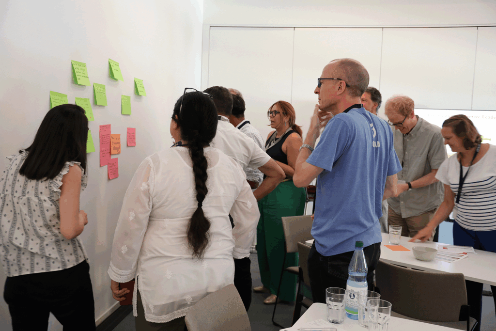  Leading Together participants involved in group work using a wall and post-it notes